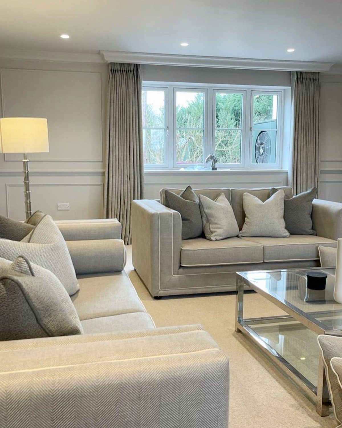 Beige curtains framing white windows in a grey and beige living room.