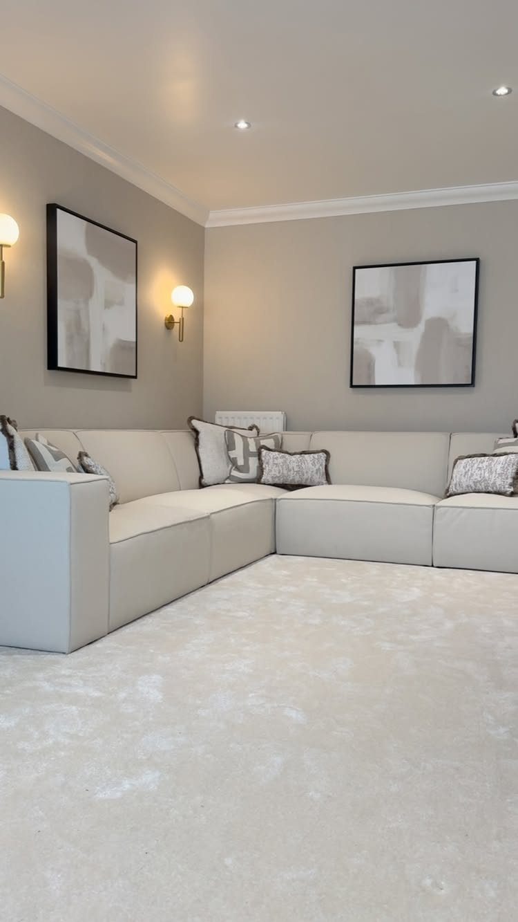 Beige sectional sofa in a living room with grey walls and abstract art.