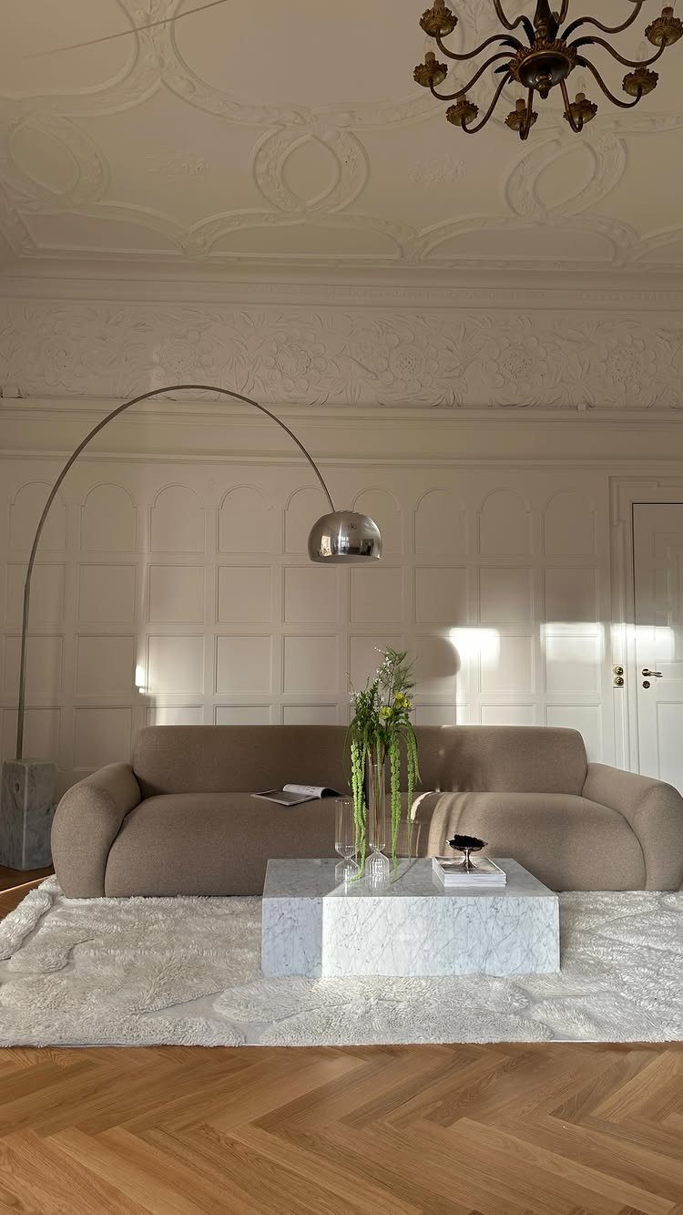 Beige sofa on a white textured rug with a white marble coffee table.