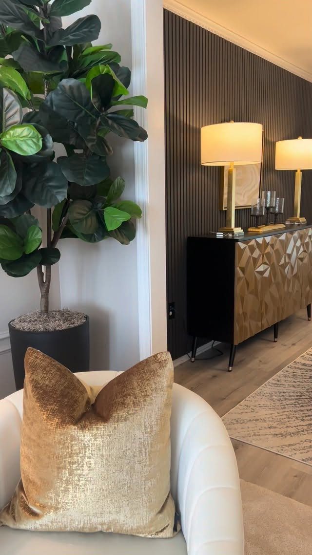 Black slatted accent wall with gold lamps and a gold geometric sideboard.