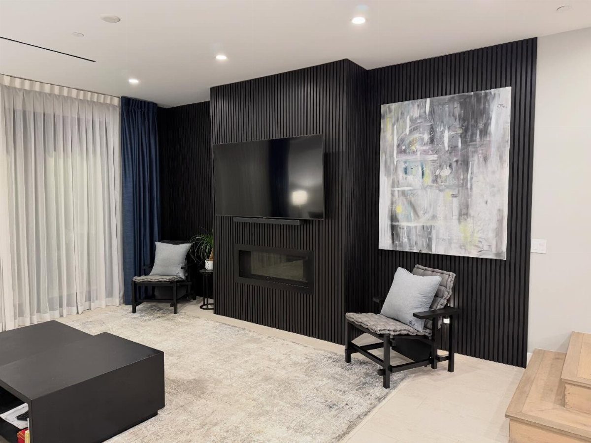 Black slatted acoustic wall with a fireplace and television in a modern living room.