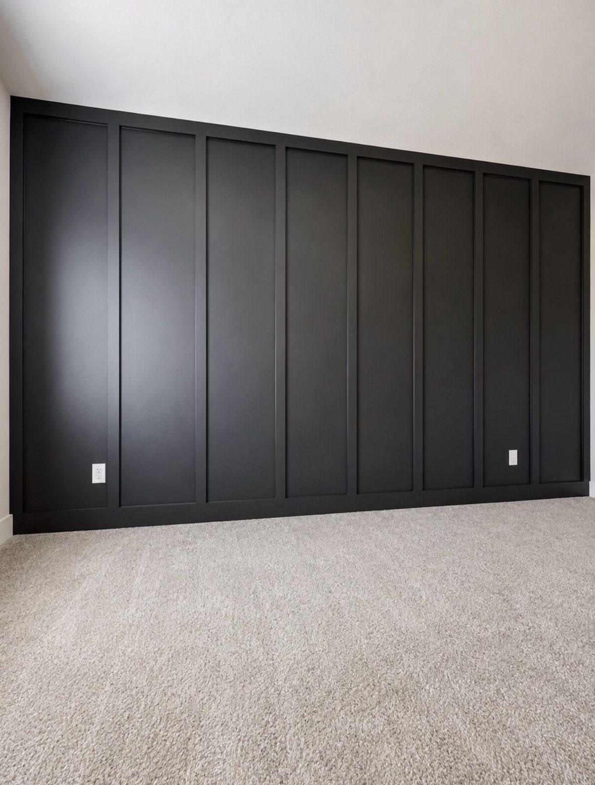 Matte black board and batten accent wall with vertical panels in a carpeted room.