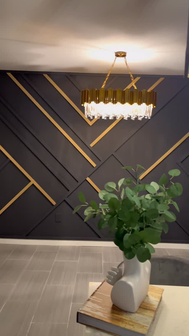 17 Black and Gold Living Room Ideas for Luxe Style 2 Black accent wall with geometric gold strips and a crystal gold chandelier.