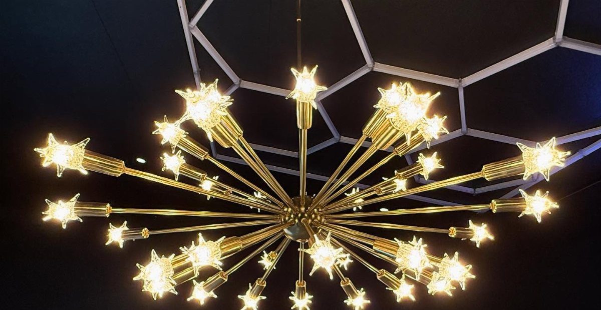 17 Black and Gold Living Room Ideas for Luxe Style 10 Gold starburst chandelier with radiating arms and star-shaped lights against a dark ceiling.