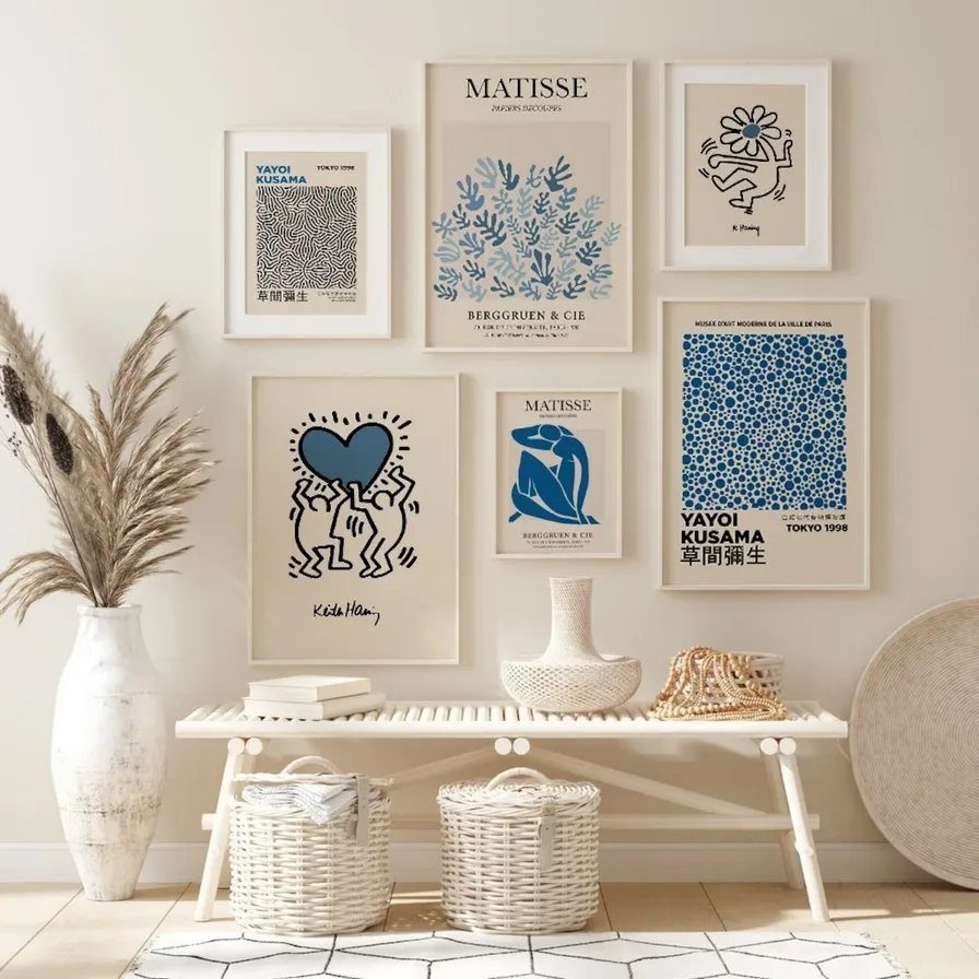 Blue and white art prints arranged in a gallery wall above a white bench.