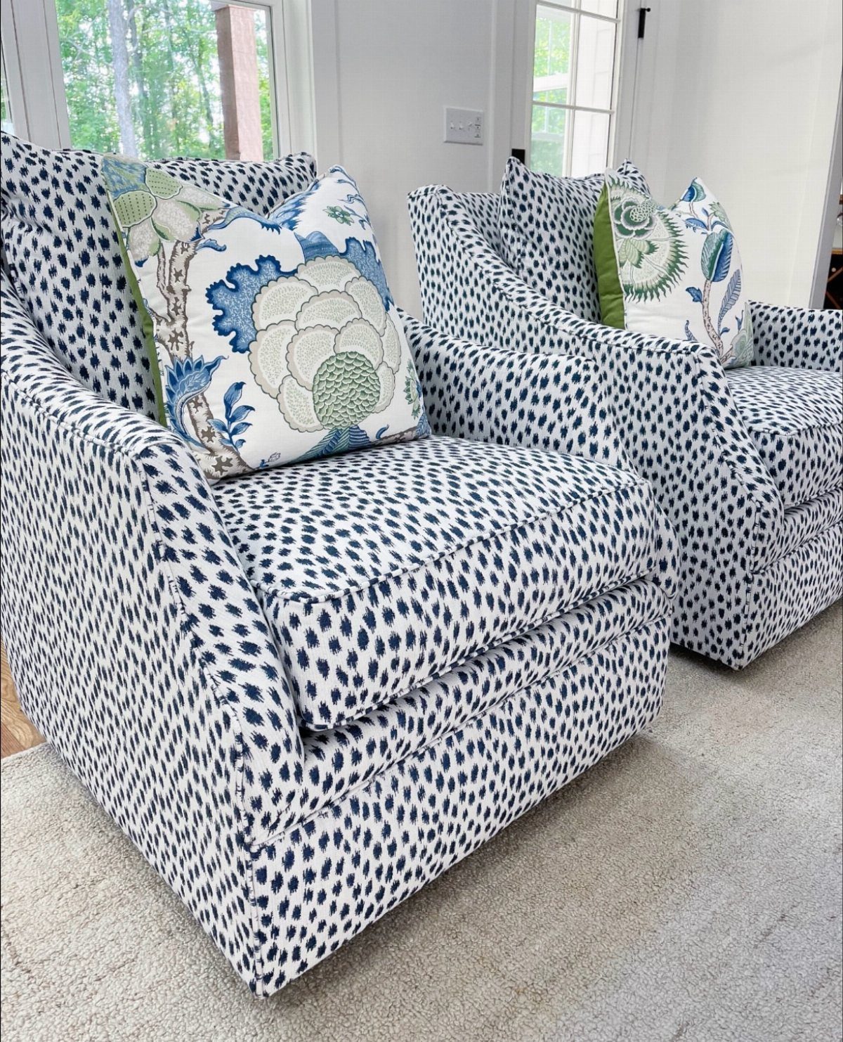 Two blue and white spotted armchairs with floral decorative pillows on grey carpet.