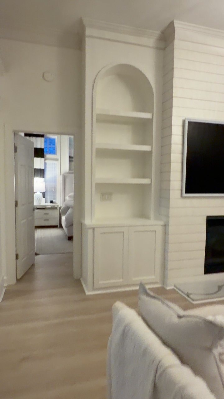 White built-in arched bookshelves and cabinets integrated into a living room wall.