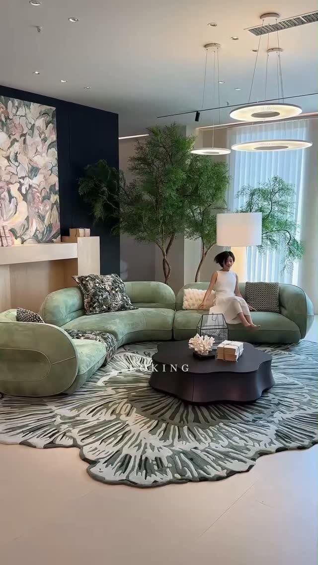 Curved light green sofa and organic coffee table on a botanical patterned rug.