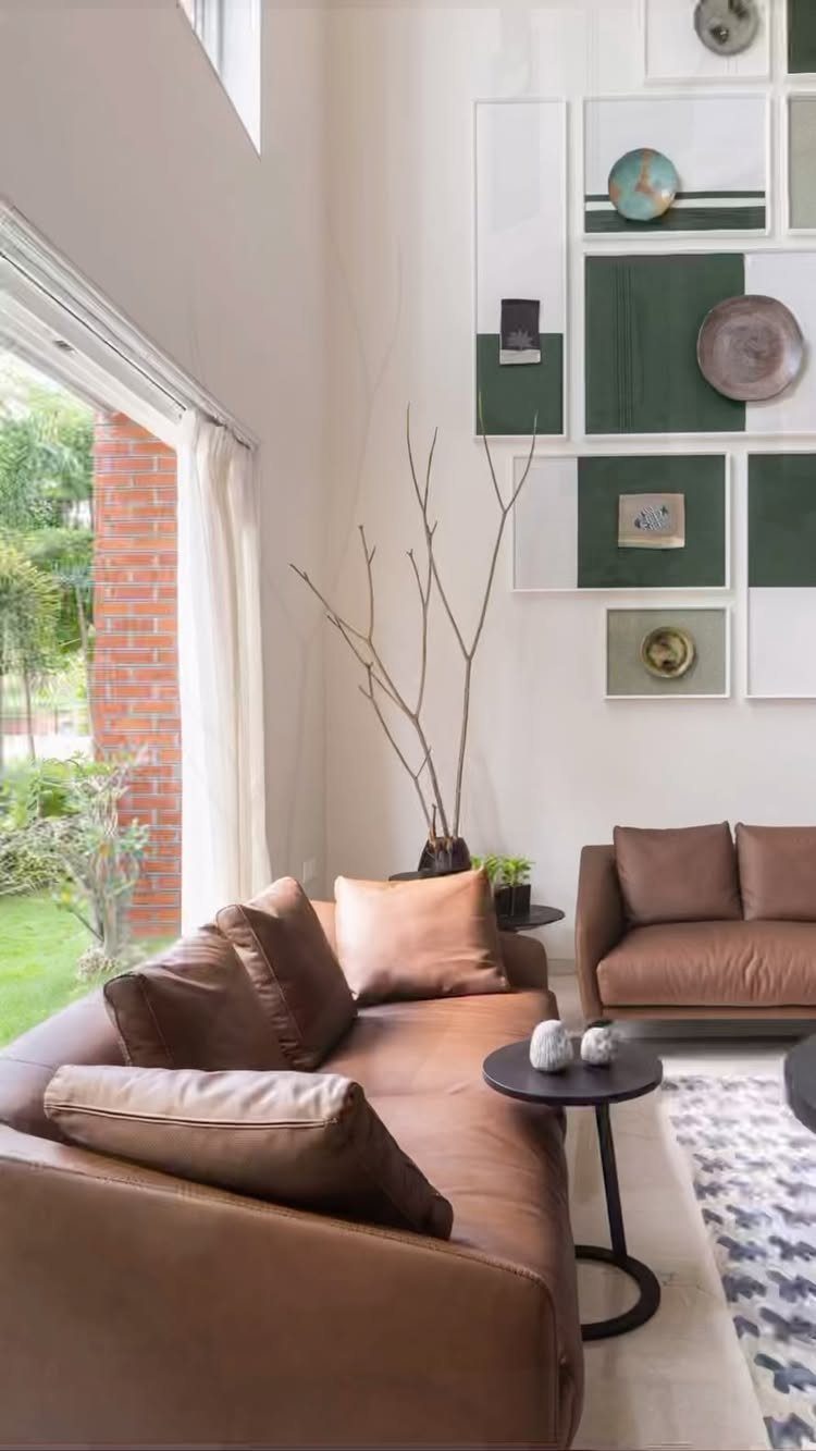 Brown leather sofas and green wall art panels in a bright modern living room.
