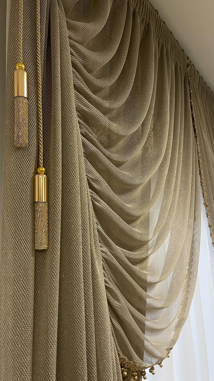 Gold textured curtains with a draped swag valance and decorative tassels.