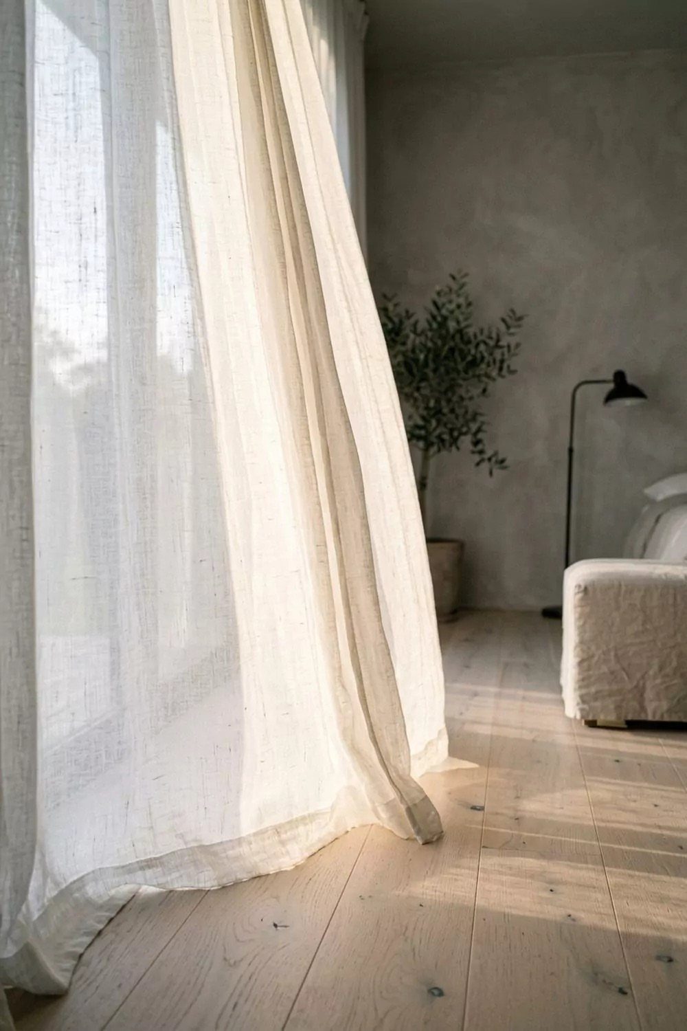Sheer white linen curtains in a bright living room with light wood flooring.