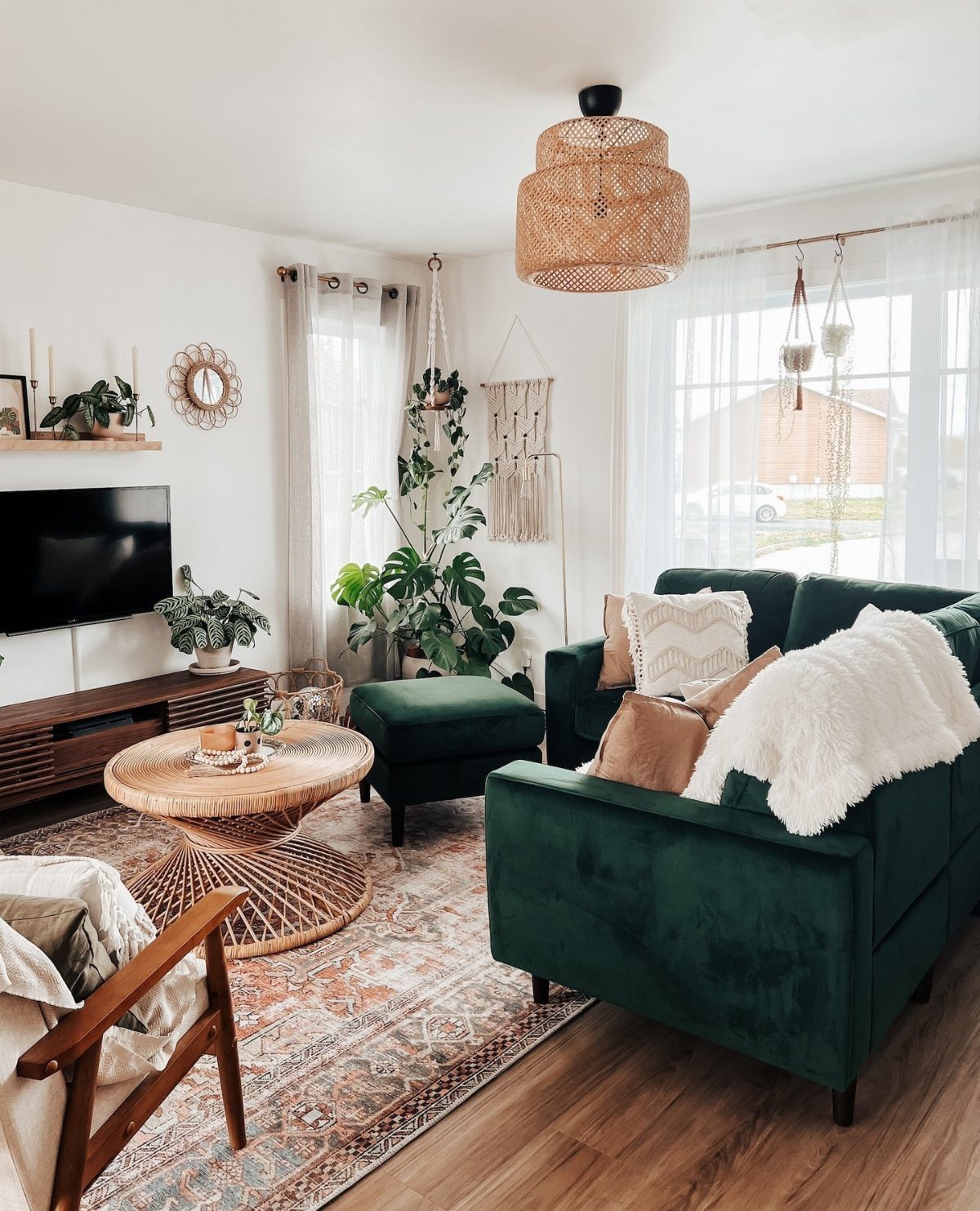 Deep green velvet sofa with a matching ottoman in a bright boho living room.
