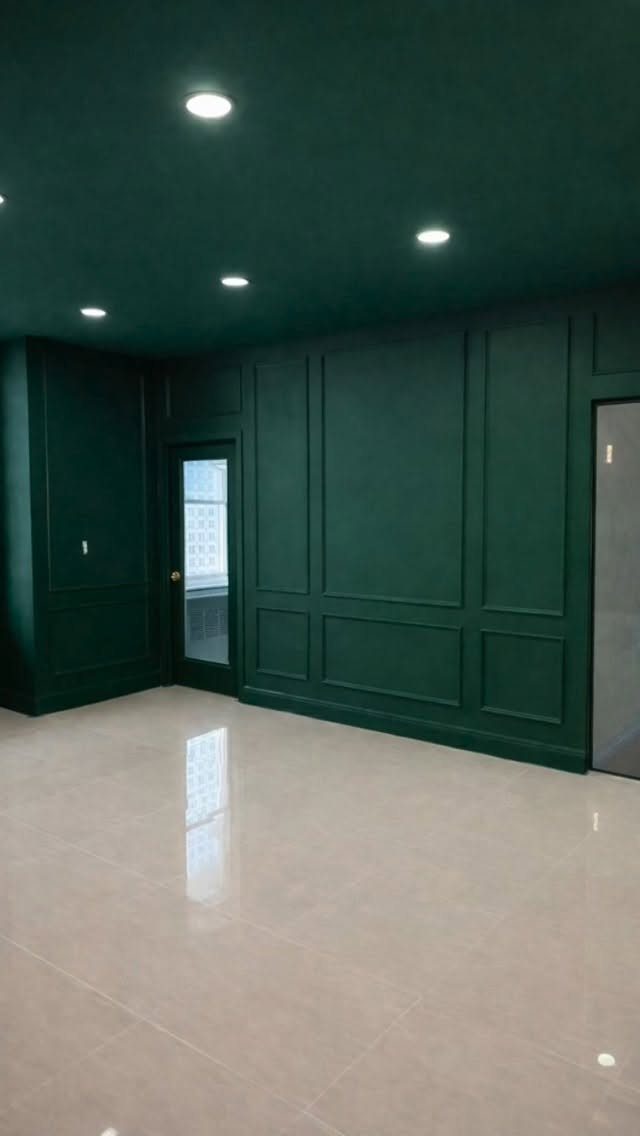 Dark green room with wall molding, matching ceiling, and polished light tile flooring.