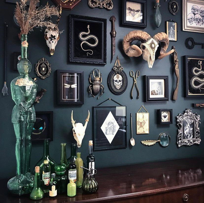Gothic gallery wall with animal skulls and framed art on dark teal paint.