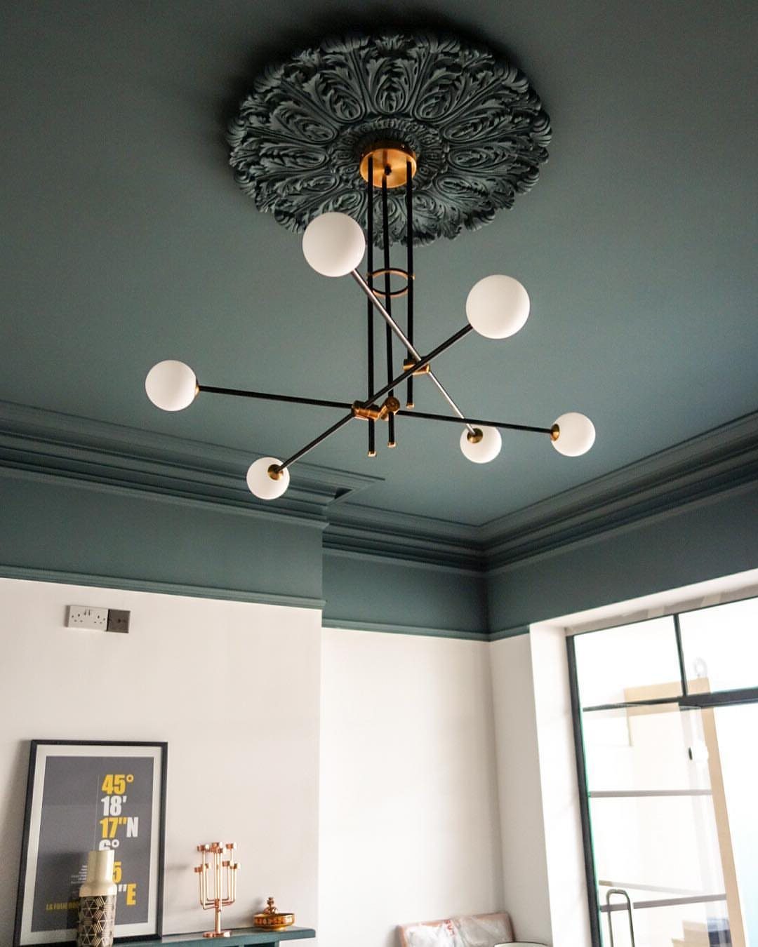 Dark teal ceiling with an ornate ceiling rose and a modern globe chandelier.