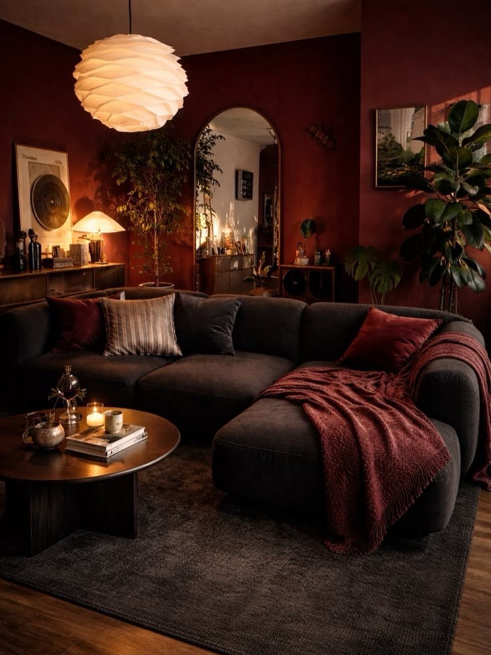 Dark charcoal gray sectional sofa in a living room with deep red walls.