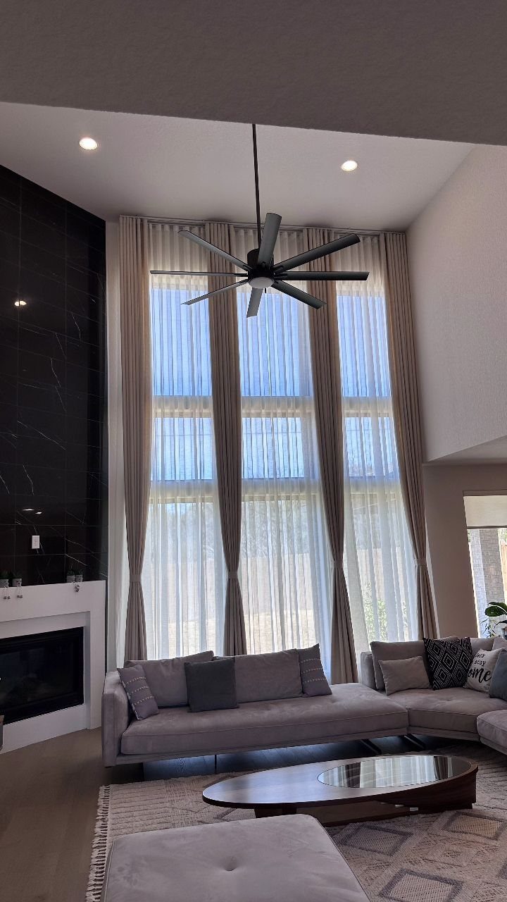 Beige drapery panels layered over white sheer curtains in a modern living room.