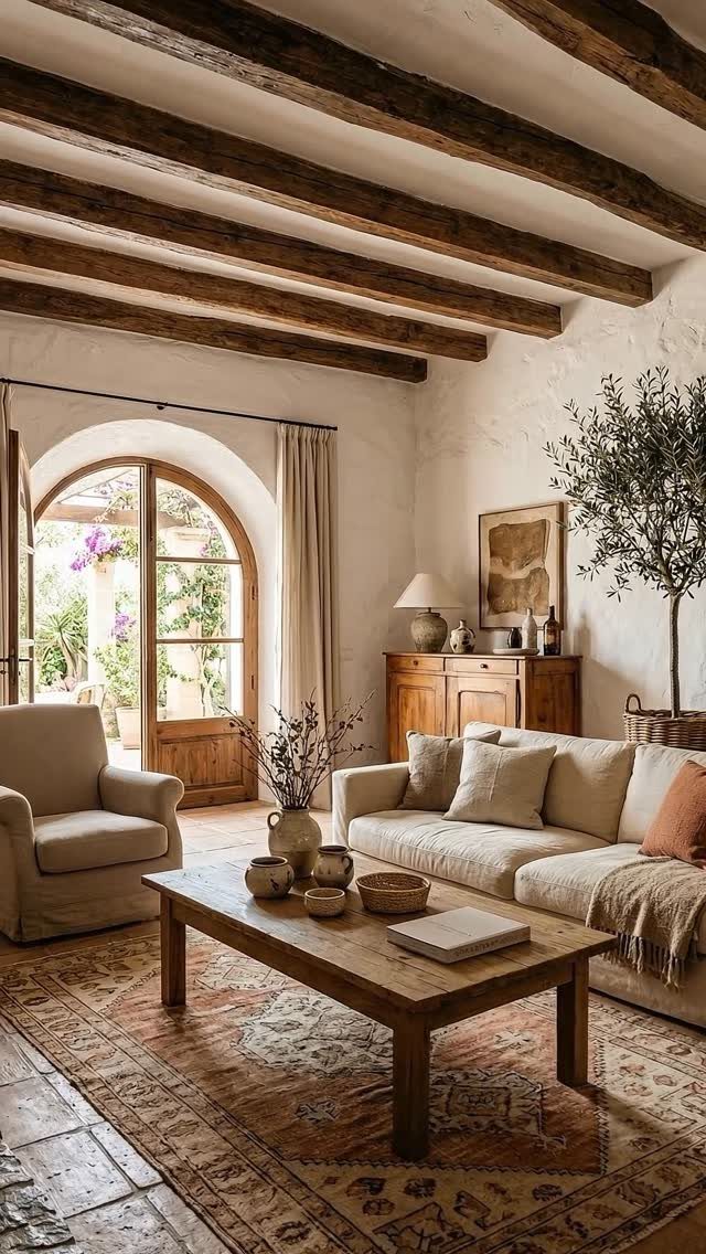 Rustic living room with exposed beams, beige furniture, and earth tone patterned rug.