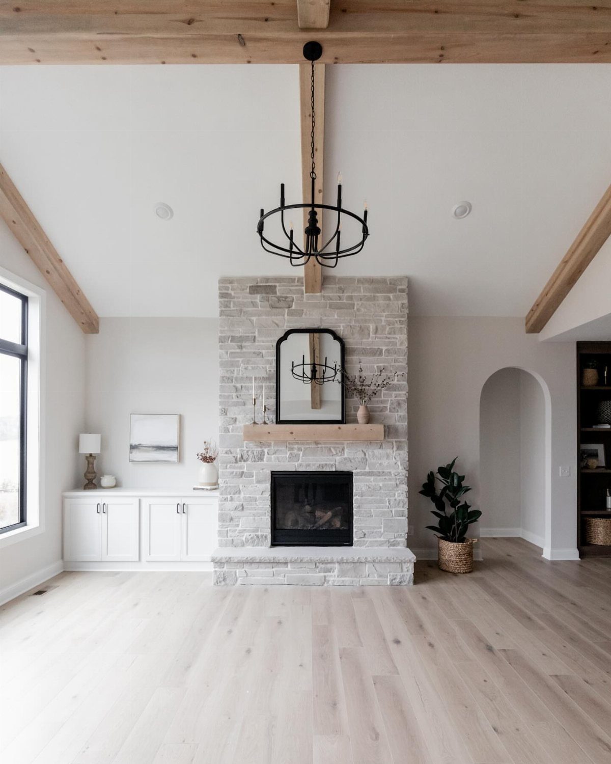 High vaulted ceiling living room with exposed beams and a stone fireplace.