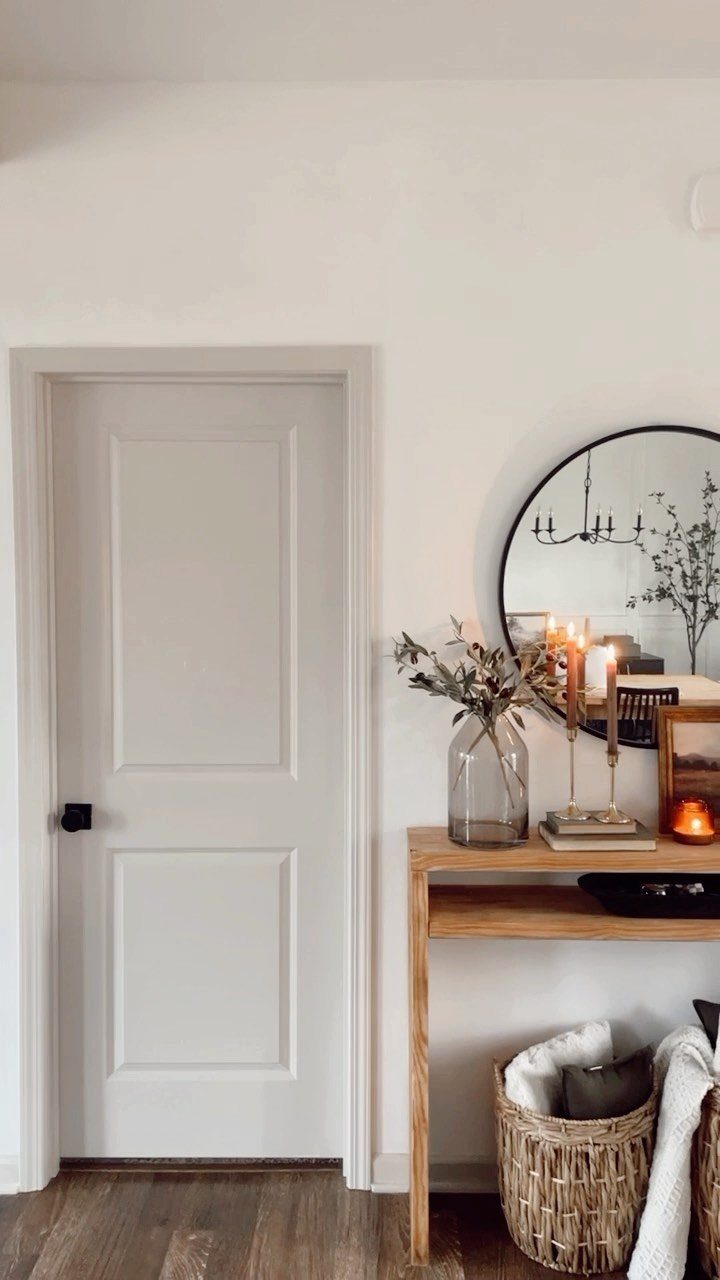 Off-white walls and trim with a wooden console table and round mirror.