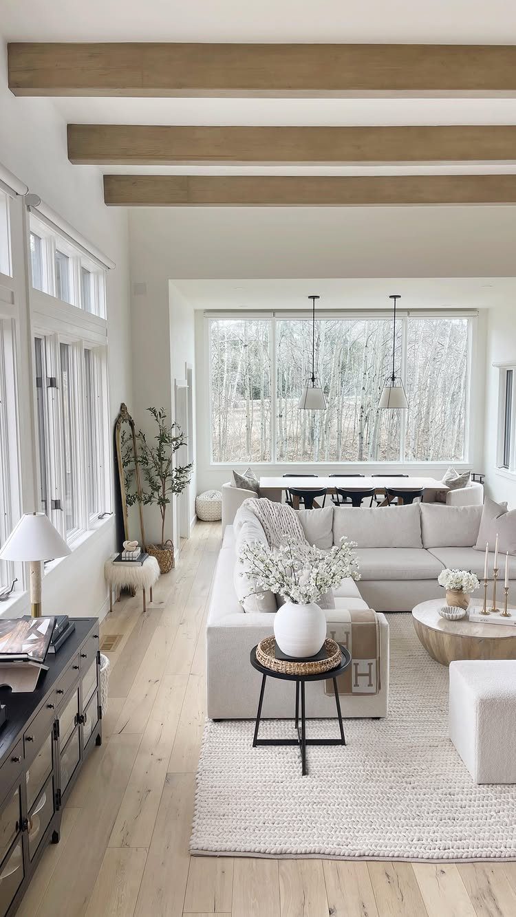 White living room with natural wood ceiling beams and light wood flooring