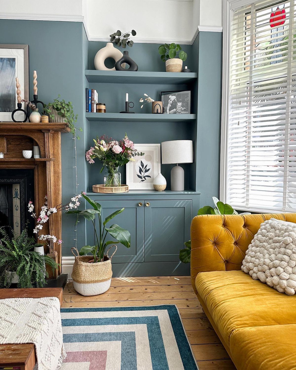 Blue-grey built-in floating shelves in a living room with a yellow velvet sofa.