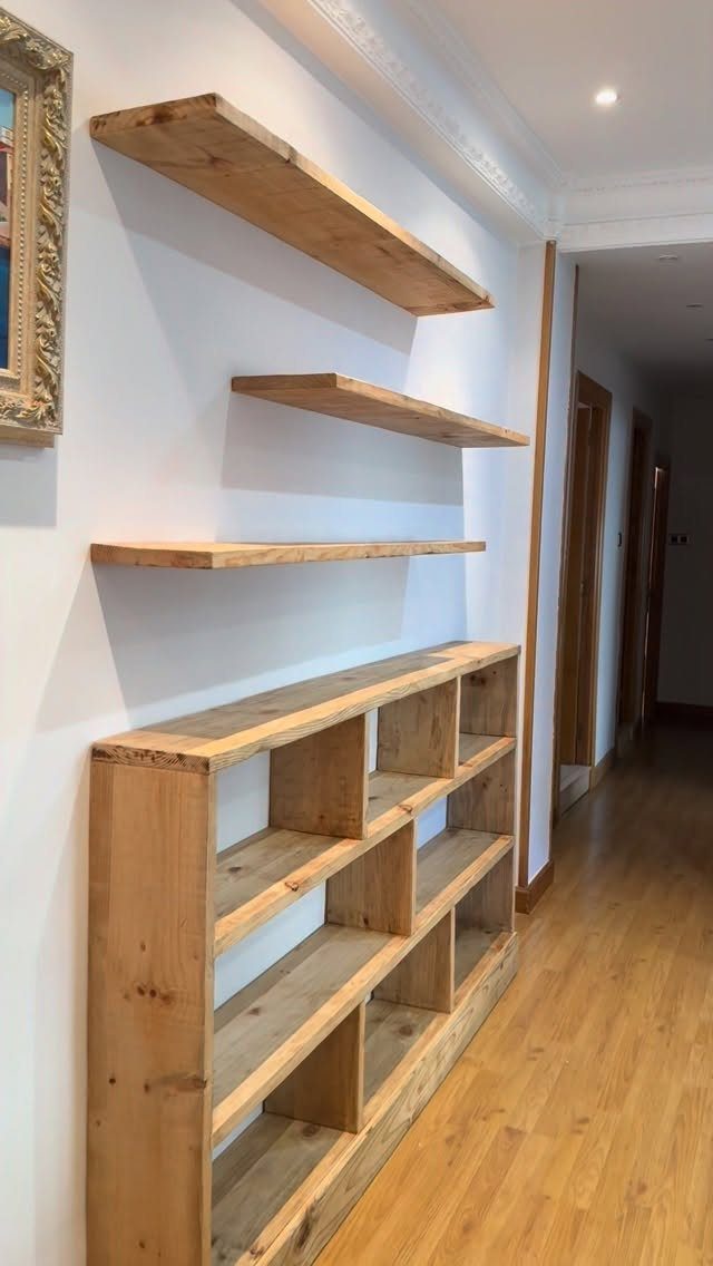 Wooden floating shelves and a matching low shelf unit on a white wall.