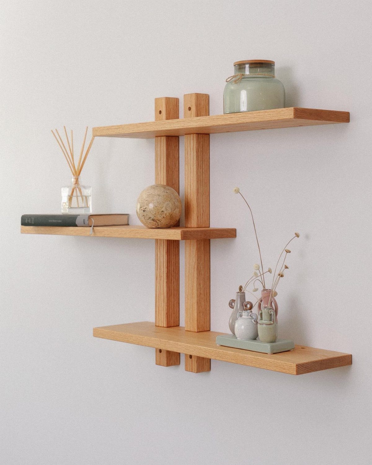 Wooden floating shelves on a white wall with minimalist home decor accessories.