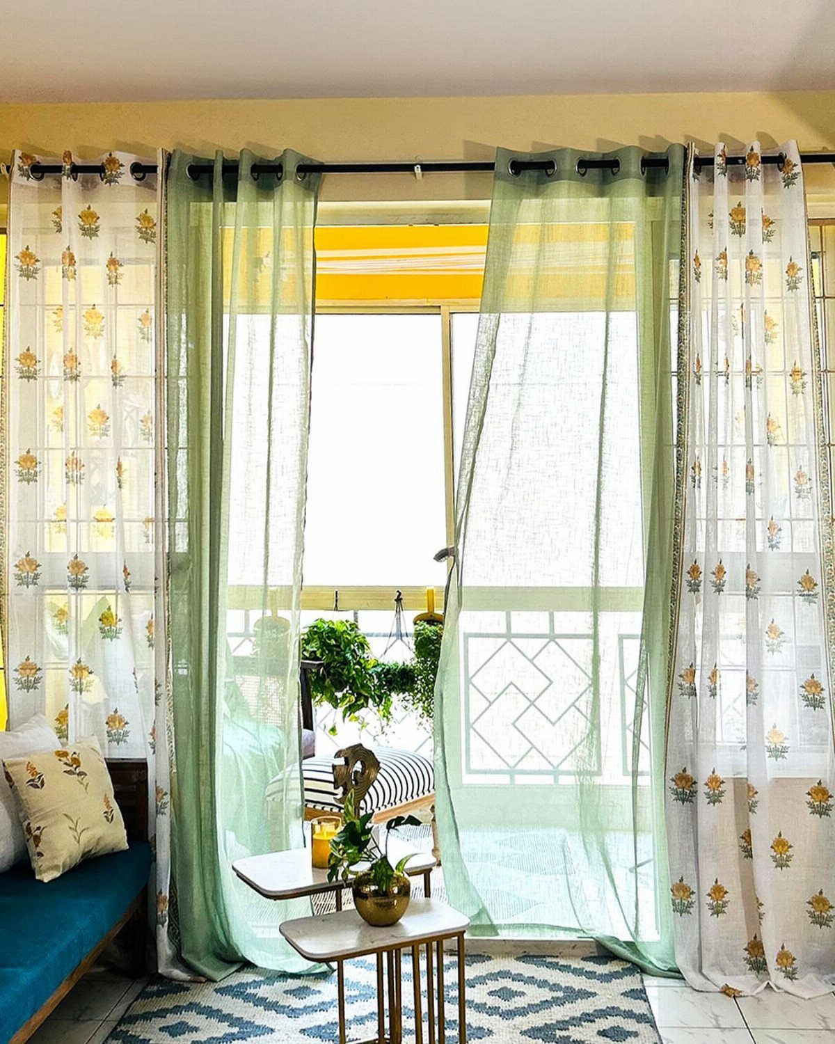 Light green and orange floral curtains framing a bright window in a living room.