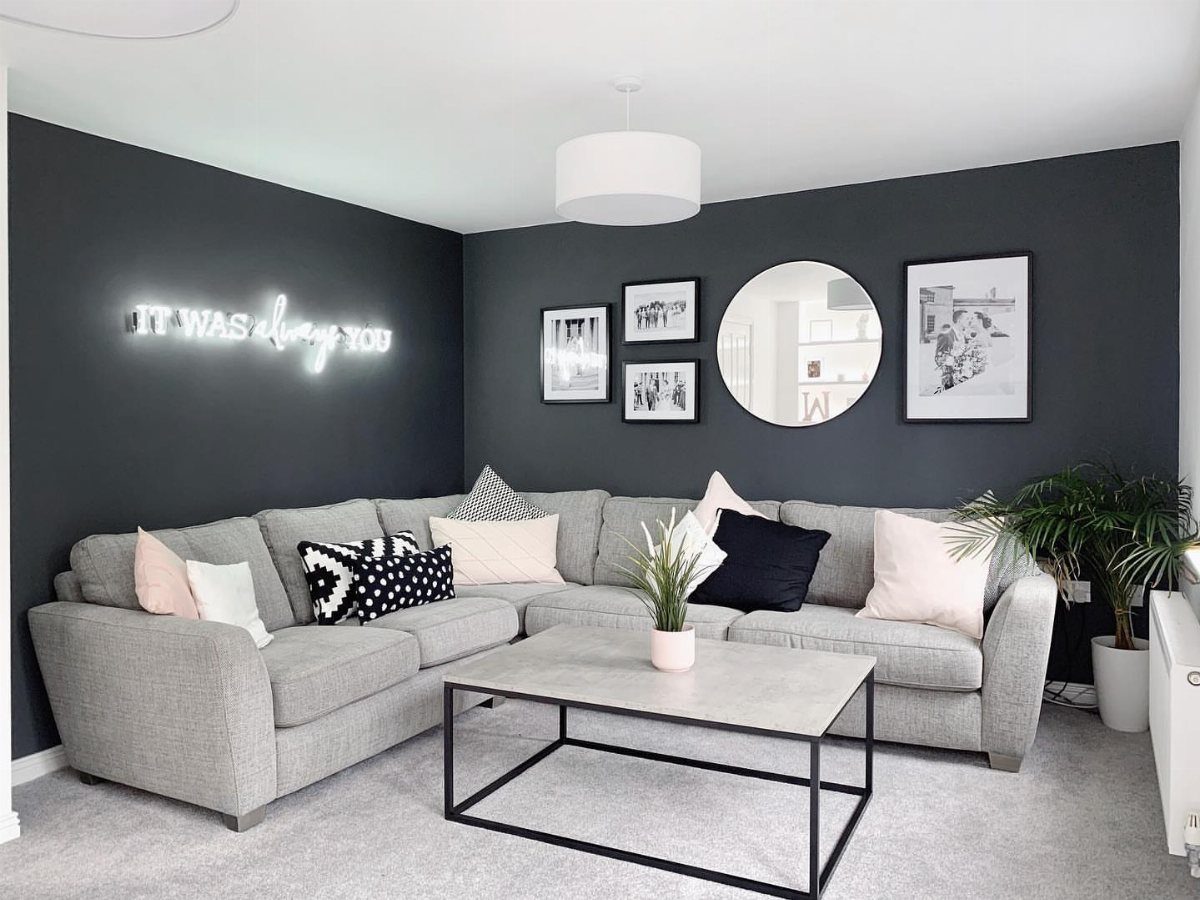 15 Grey Sofa Living Room Ideas with Real Style 14 Light grey sectional sofa with a round mirror and neon sign on dark walls.