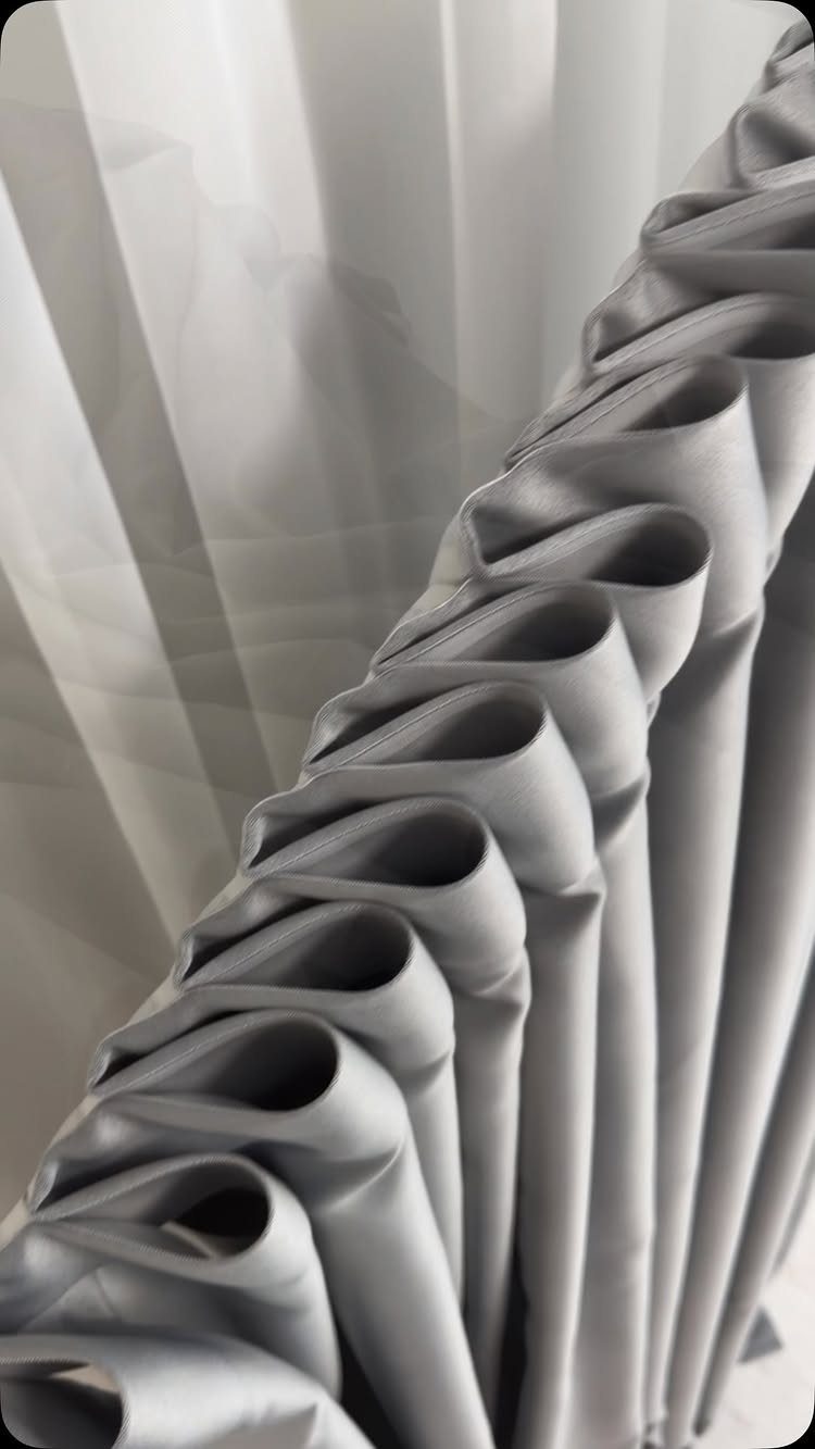 Light grey pleated curtains with deep folds gathered at the top header.