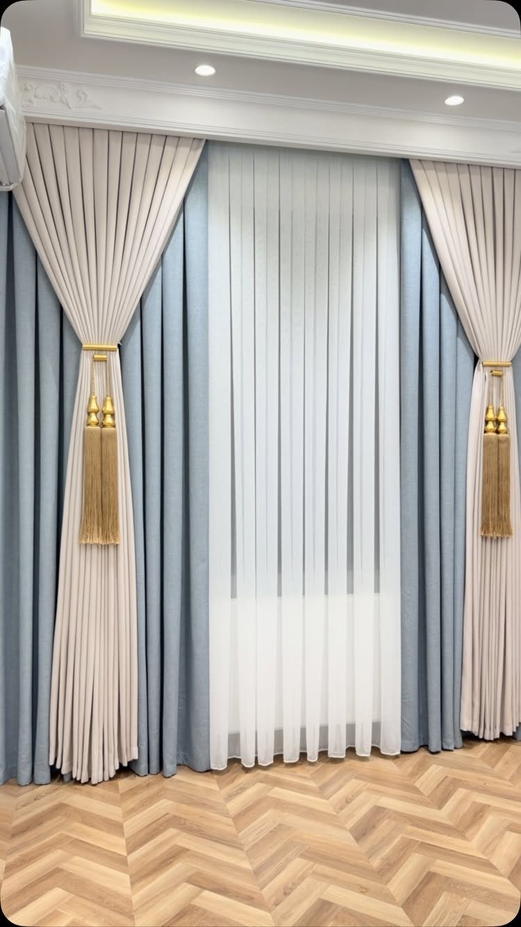 Cream and light blue living room curtains with gold tassels on herringbone floors
