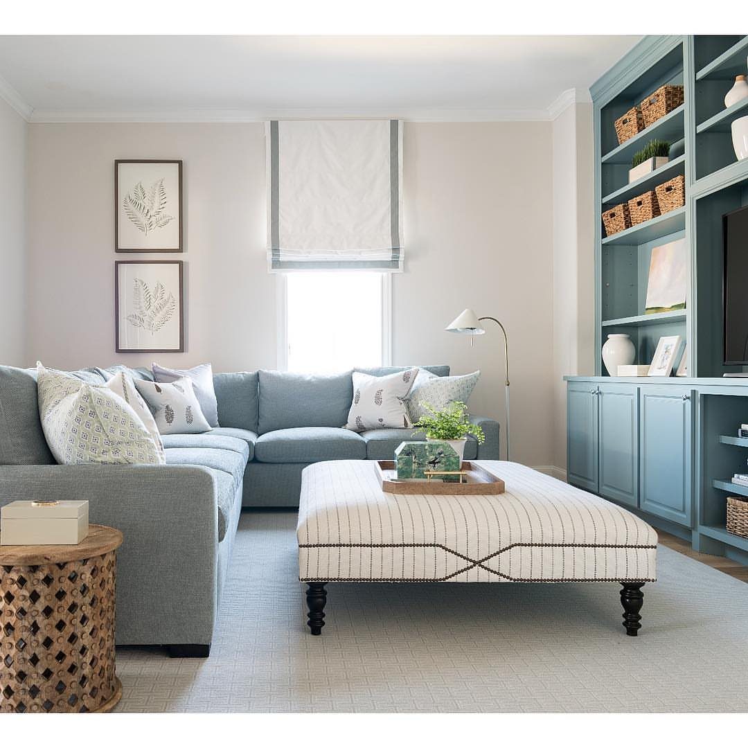 Light blue built-in shelves and a matching blue sectional sofa in a bright living room.