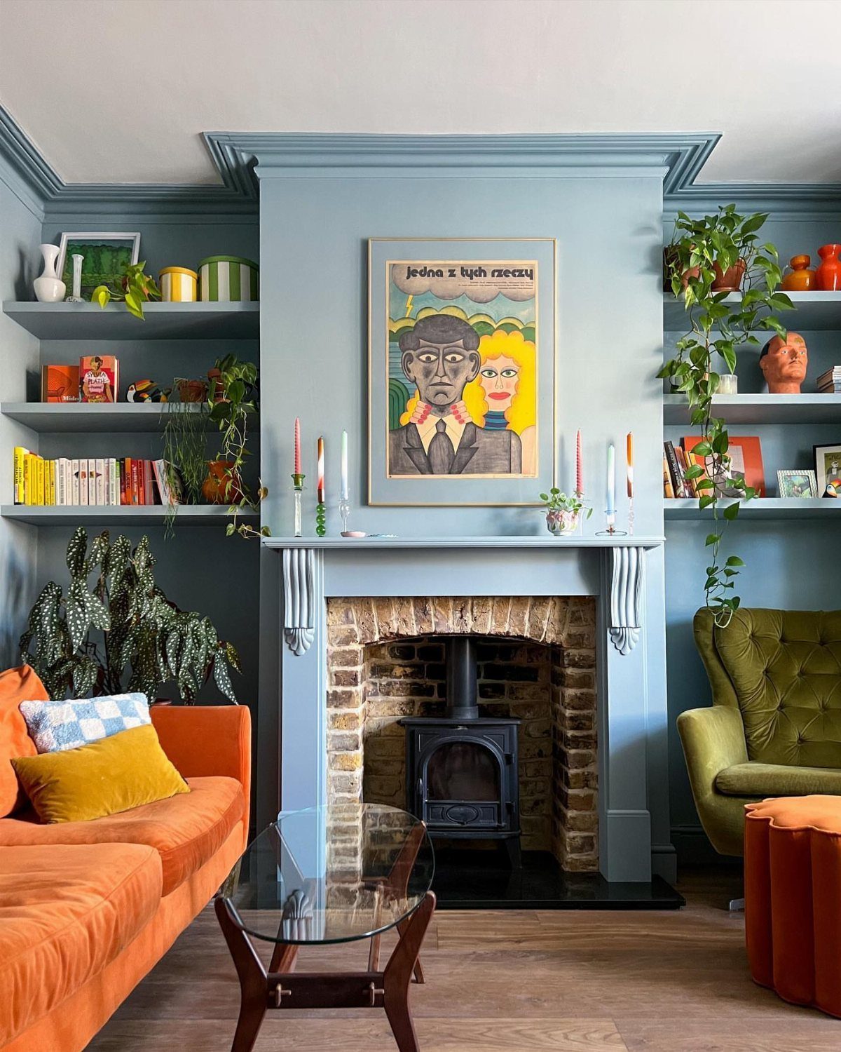 Light blue living room with orange sofa, green armchair, and brick fireplace.