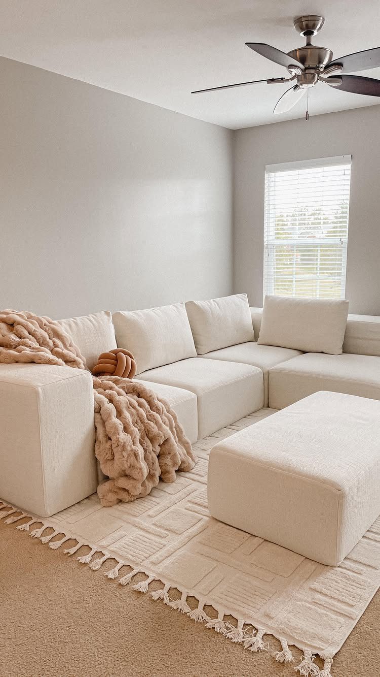 9 Living Room Couch Ideas for a Stylish Space 3 Cream L-shaped sectional sofa with a matching ottoman and chunky knit throw blanket.