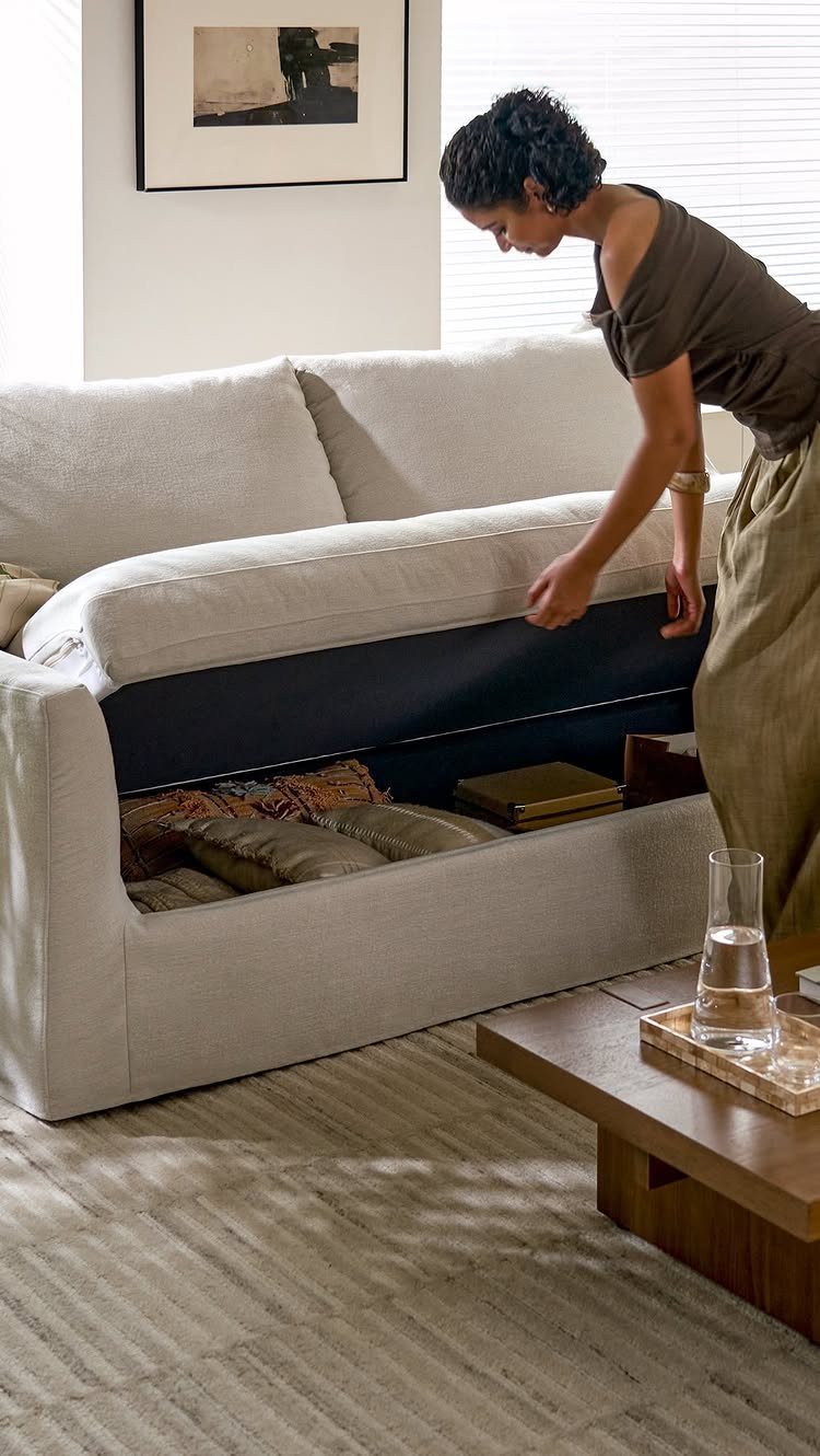 9 Living Room Couch Ideas for a Stylish Space 5 Woman opening a hidden storage compartment under the seat of a beige sofa.