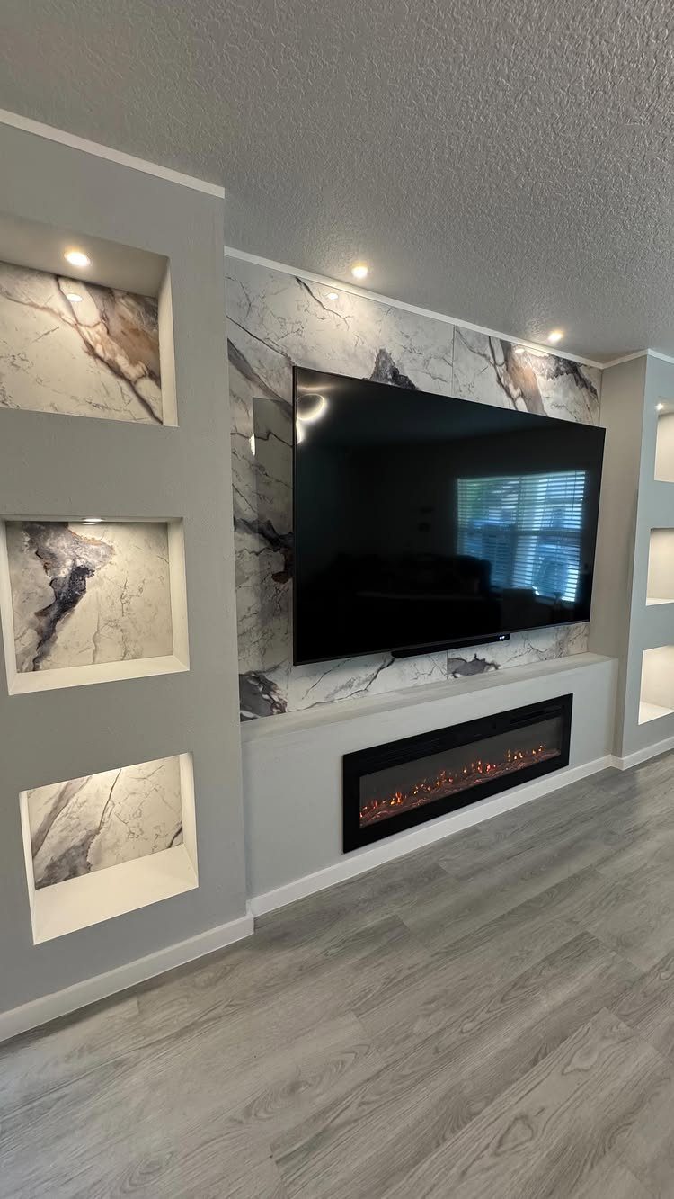 Modern living room wall with built-in recessed shelves, marble accents, and a fireplace.