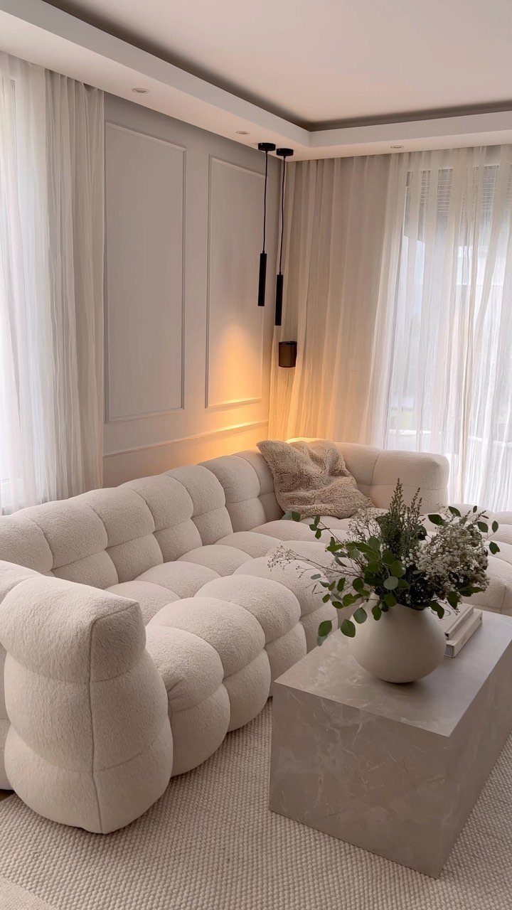White modular tufted sofa with a stone coffee table in a neutral living room.