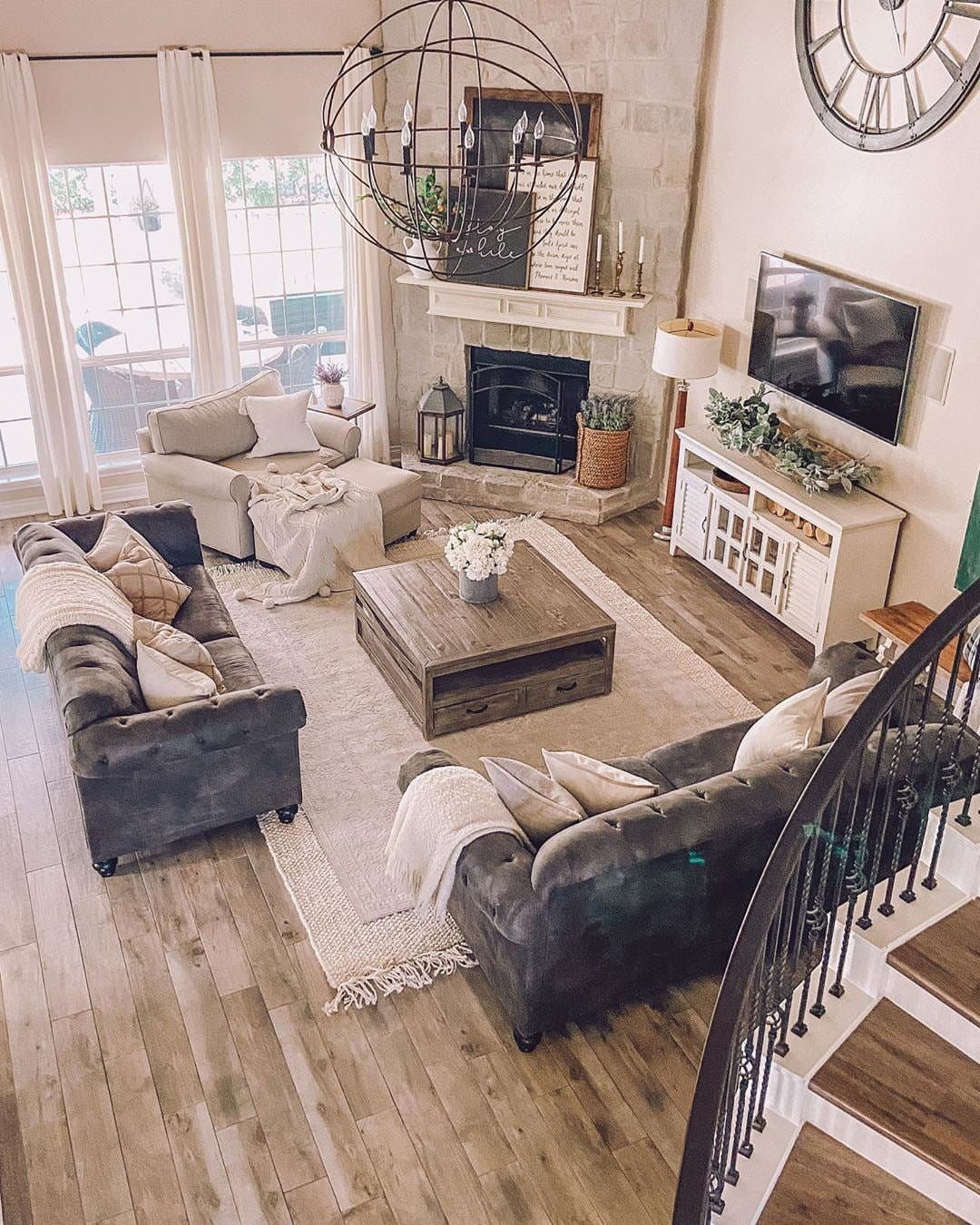 Living room with grey sofas, beige armchair, light area rug, and cozy throw blankets.