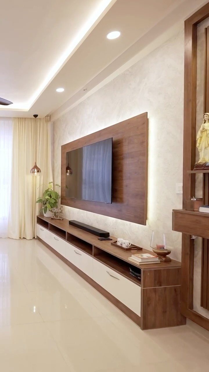 Wall-mounted TV on wood panel with a long white and brown entertainment console.
