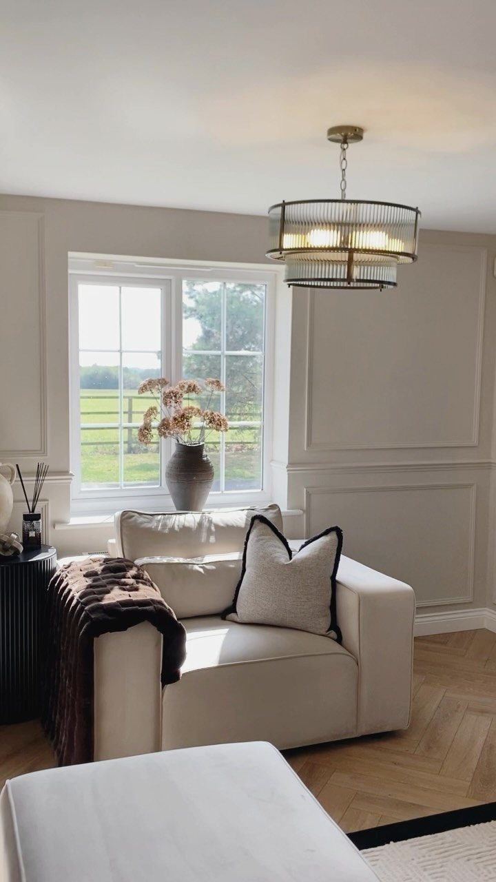 Tiered glass and metal pendant light hanging in a bright, modern living room.