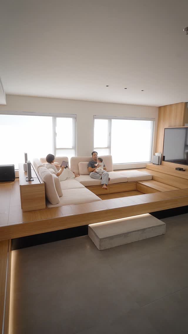 Built-in wooden platform with white cushions in a bright, modern living room.