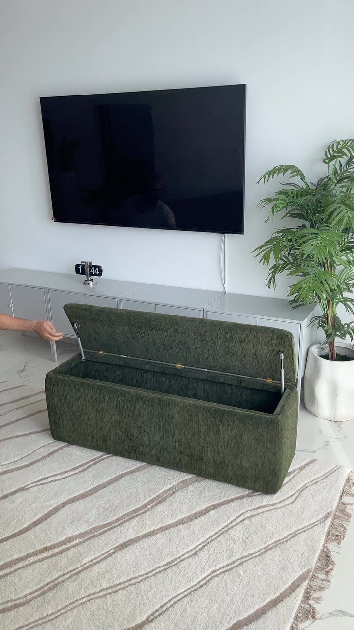 Green storage ottoman on a patterned rug in a modern living room