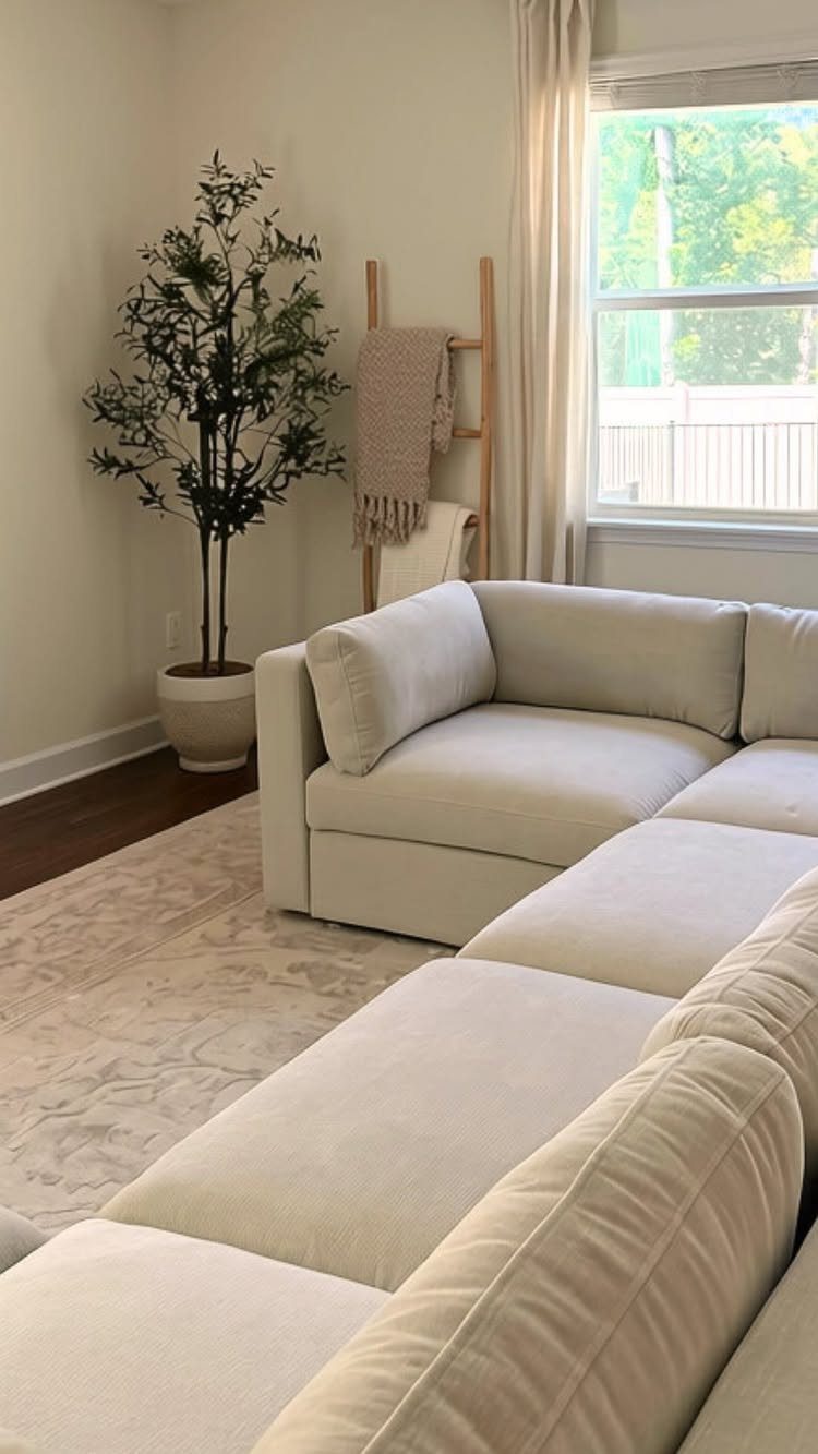 Cream sectional sofa in a bright living room with a decorative wooden ladder.