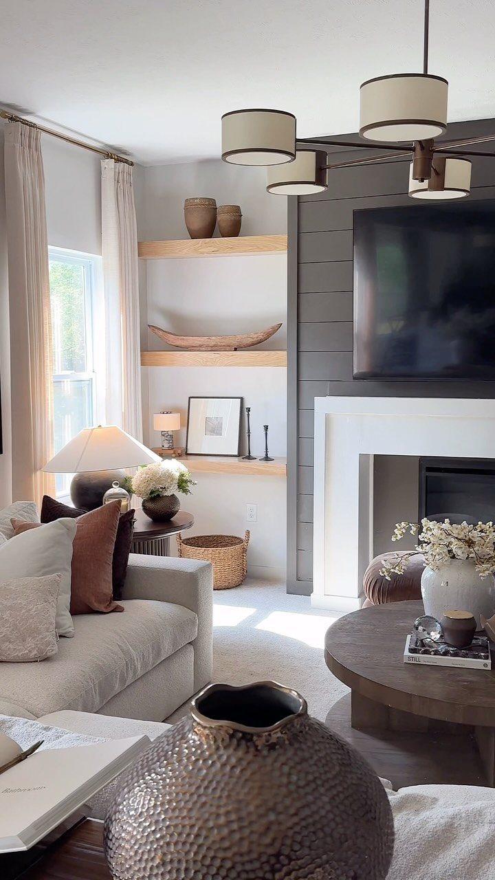Wooden floating shelves with decor on a white wall in a modern living room.