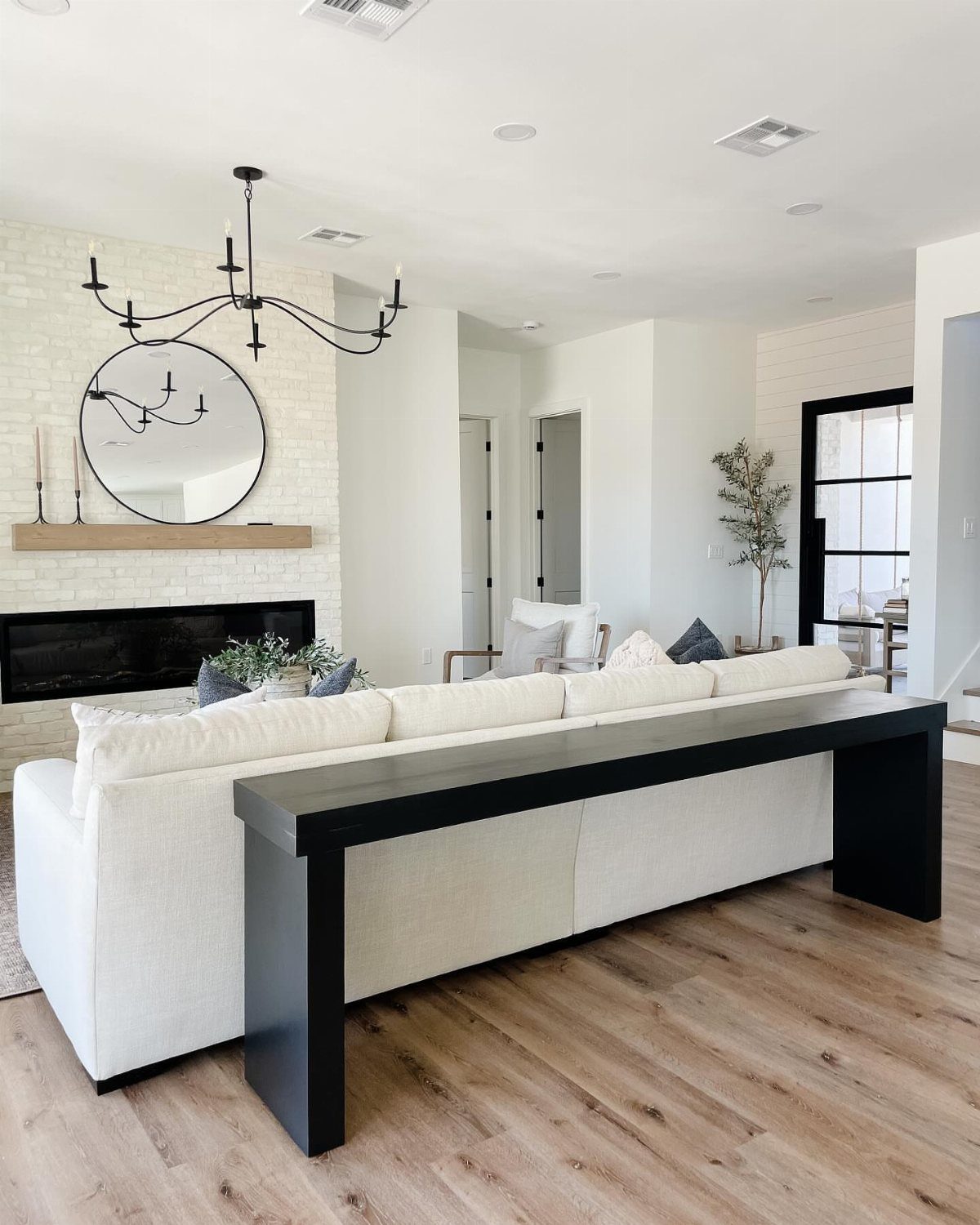 Black console table placed behind a white sofa in a modern bright living room.