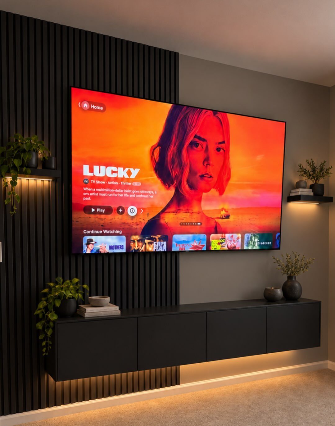 Black floating wall-mounted cabinets under a large television on a slatted accent wall.