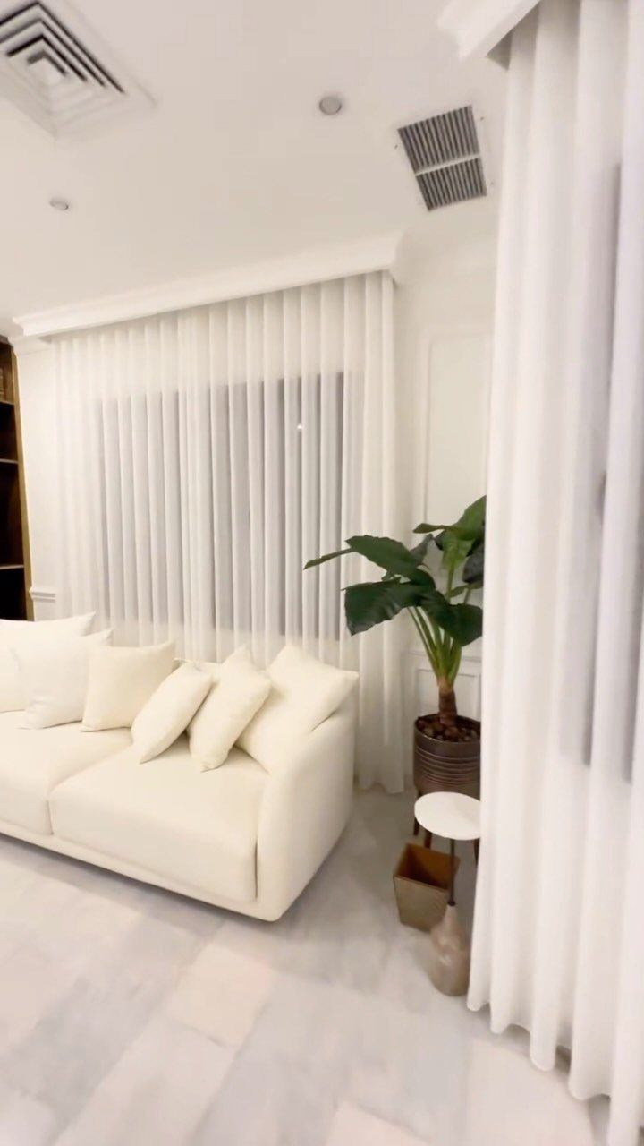 White living room with a white sofa and sheer curtains under a valance.