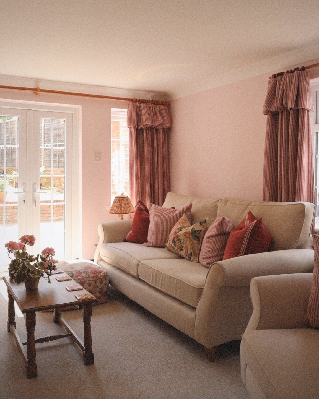 Pink gathered valances and curtains in a living room with a beige sofa.