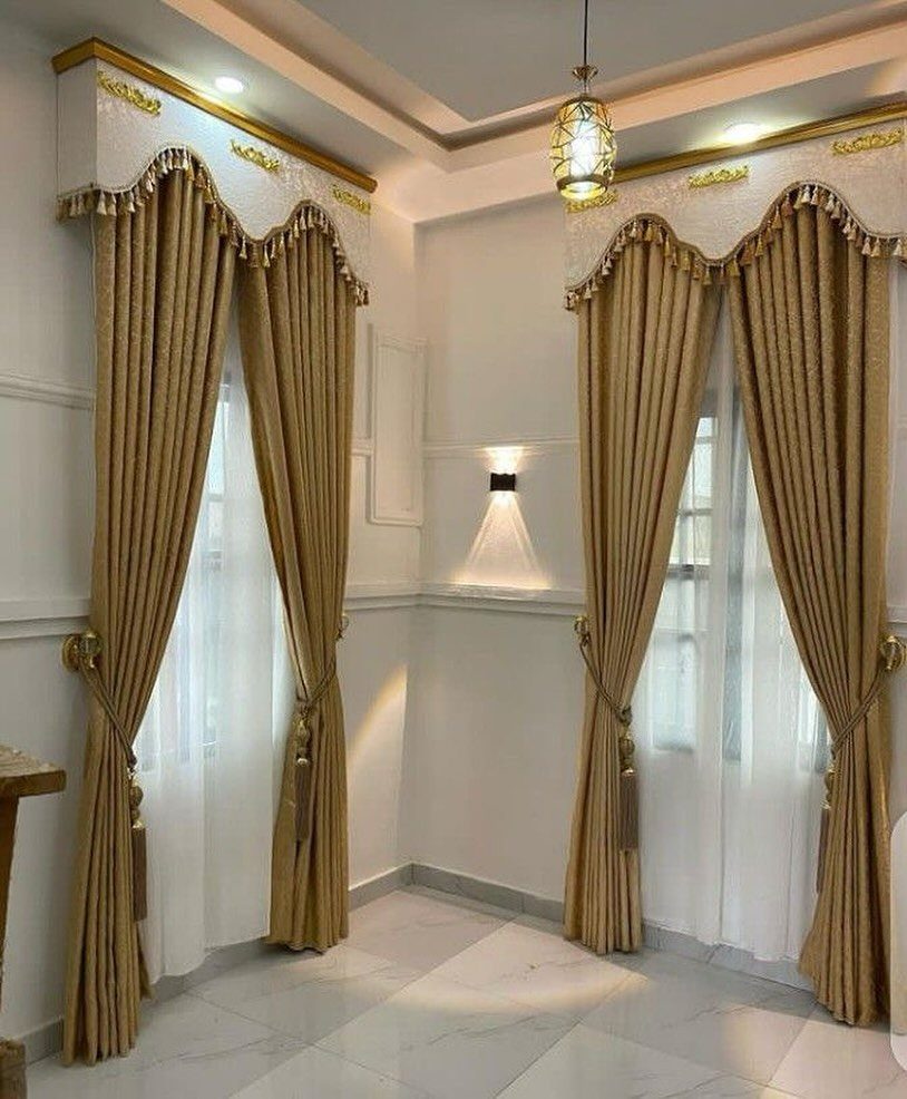 Gold curtains with scalloped valances and fringe trim in a bright white room.
